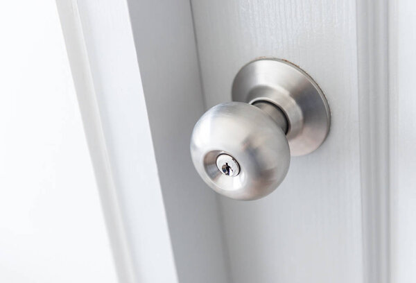 white door with metal doorknob is regular lock style in a house.