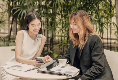 İki iş kadınları grafik evrak masaya tartışıyor.