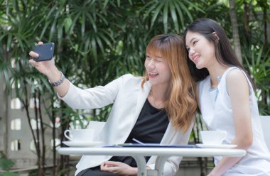 İki genç kadın selfie akıllı telefon ile elinden alarak ve Bahçe, kentsel yaşam kavramı gülümseyen güzel.