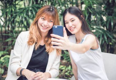 İki genç kadın selfie akıllı telefon ile elinden alarak ve Bahçe, kentsel yaşam kavramı gülümseyen güzel.