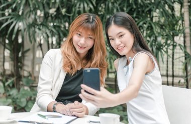 İki genç kadın selfie akıllı telefon ile elinden alarak ve Bahçe, kentsel yaşam kavramı gülümseyen güzel.