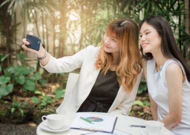İki genç kadın selfie akıllı telefon ile elinden alarak ve Bahçe, kentsel yaşam kavramı gülümseyen güzel.