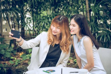 İki genç kadın selfie akıllı telefon ile elinden alarak ve Bahçe, kentsel yaşam kavramı gülümseyen güzel.