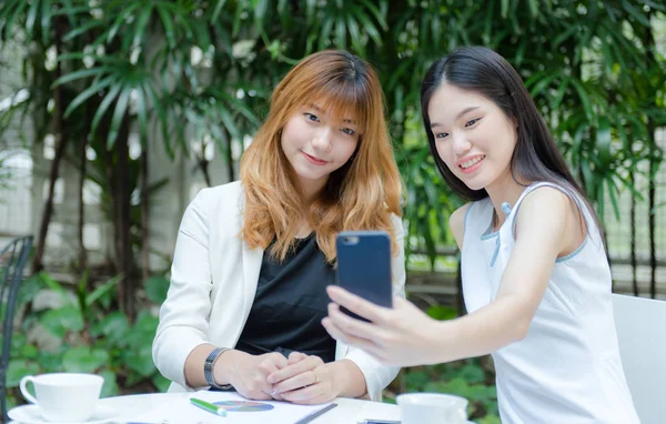 İki genç kadın selfie akıllı telefon ile elinden alarak ve Bahçe, kentsel yaşam kavramı gülümseyen güzel.