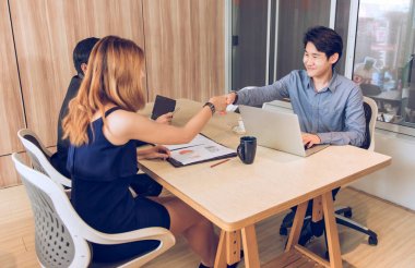 Mutlu Asya işadamı ve kadın ofiste el sallamak, anlaşma kavramı üzerinde bir anlaşma.