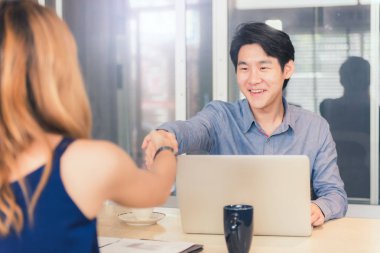 Mutlu Asya işadamı ve kadın ofiste el sallamak, anlaşma kavramı üzerinde bir anlaşma.