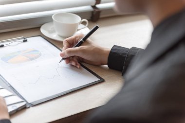 ofisindeki masanın üzerine kalem ile konsantre belgeler grafik üzerinde işadamı.