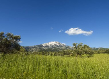 Yunanistan'ın Evia adasında bulutlarla kaplı kar kaplı dağ Dirfys, kilise ve gökyüzünün panoramik manzarası