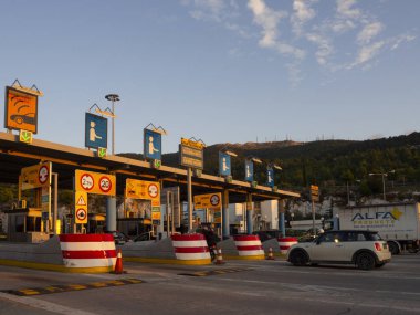 Central Greece. December 2019: Trip on the toll highway Athens-Thessaloniki, past cars, gas stations, toll checkpoints at sunset in the summer evening