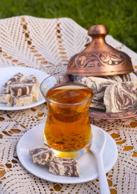 Güneşli bir günde el yapımı masa örtüsü ve şeker makinesi olan bir masada Türk çayı ve mermer halkası.
