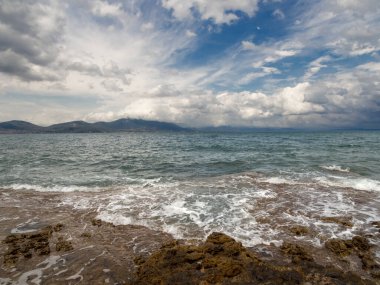 Yunanistan 'ın Evia adasında bir yaz günü, Ege Denizi' nde sersemletici fırtına bulutları, dalgalar ve kayalık plajların panoramik manzarası