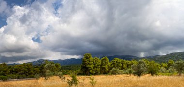 Yunanistan 'daki Evia adasındaki bahar fırtınasından önce köyün panoramik manzarası, dağlar ve gökyüzü kara fırtına bulutlarıyla kaplı.