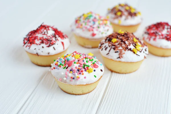 Cupcakes with white cream  and sprinkles on white background — Stock Photo, Image
