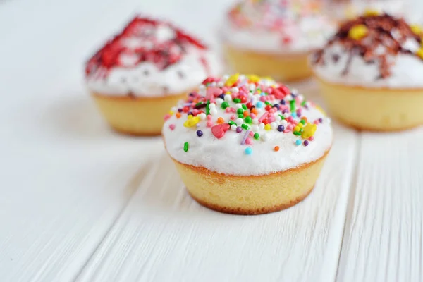 Cupcakes con crema blanca y espolvoreos sobre fondo blanco — Foto de Stock