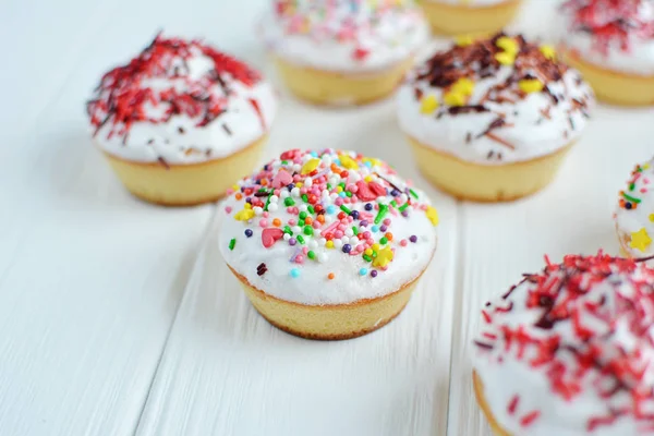 Cupcakes with white cream  and sprinkles on white background — Stock Photo, Image