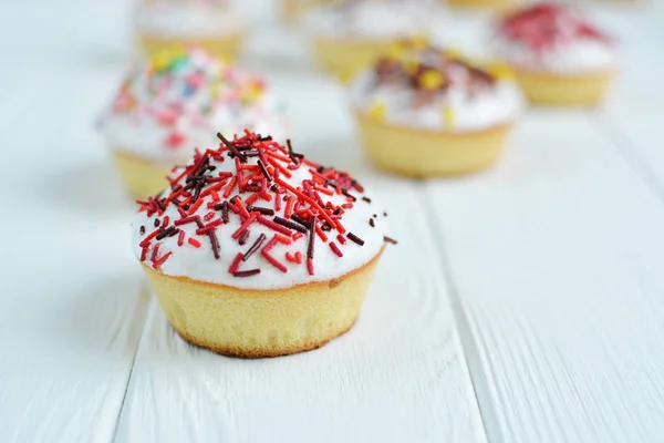 Cupcakes con crema blanca y espolvoreos sobre fondo blanco — Foto de Stock