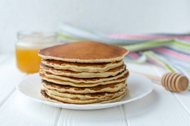 Sağlıklı kahvaltı. Ahşap arka plan üzerinde beyaz tabakta bal ile lezzetli, ev yapımı krep yığını