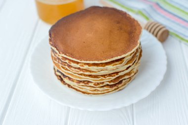 Sağlıklı kahvaltı. Ahşap arka plan üzerinde beyaz tabakta bal ile lezzetli, ev yapımı krep yığını