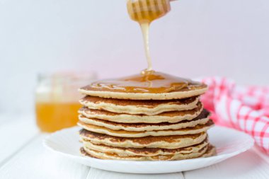 Sağlıklı kahvaltı. Ahşap arka plan üzerinde beyaz tabakta bal ile lezzetli, ev yapımı krep yığını