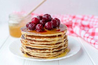 Sağlıklı kahvaltı. Bal ve beyaz tabakta kiraz ile lezzetli, ev yapımı krep yığını 