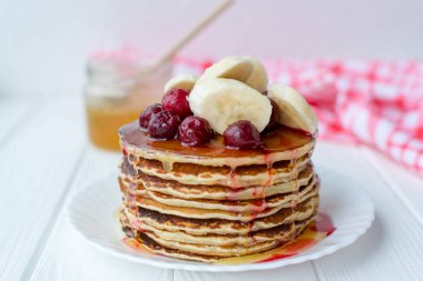 Sağlıklı kahvaltı. Tatlım, kiraz ve muz beyaz tabakta lezzetli, ev yapımı krep yığını 
