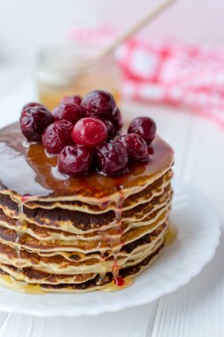 Sağlıklı kahvaltı. Bal ve beyaz tabakta kiraz ile lezzetli, ev yapımı krep yığını 