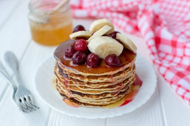 Sağlıklı kahvaltı. Tatlım, kiraz ve muz beyaz tabakta lezzetli, ev yapımı krep yığını 