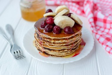 Sağlıklı kahvaltı. Tatlım, kiraz ve muz beyaz tabakta lezzetli, ev yapımı krep yığını 