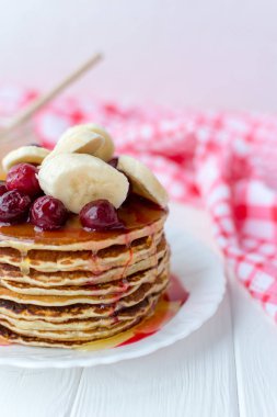 Sağlıklı kahvaltı. Tatlım, kiraz ve muz beyaz tabakta lezzetli, ev yapımı krep yığını 