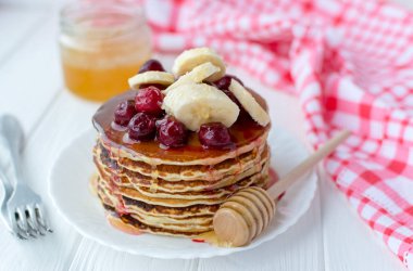 Sağlıklı kahvaltı. Tatlım, kiraz ve muz beyaz tabakta lezzetli, ev yapımı krep yığını 