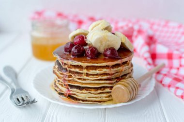 Sağlıklı kahvaltı. Tatlım, kiraz ve muz beyaz tabakta lezzetli, ev yapımı krep yığını 