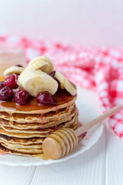 Sağlıklı kahvaltı. Tatlım, kiraz ve muz beyaz tabakta lezzetli, ev yapımı krep yığını 