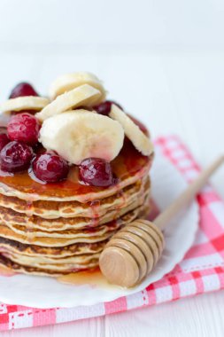 Sağlıklı kahvaltı. Tatlım, kiraz ve muz beyaz tabakta lezzetli, ev yapımı krep yığını 