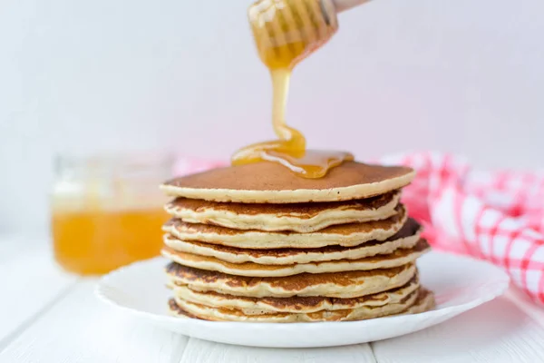 Desayuno saludable. Montón de deliciosos panqueques caseros con miel en plato blanco sobre fondo de madera — Foto de Stock