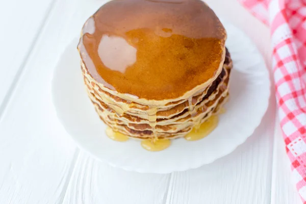 Desayuno saludable. Montón de deliciosos panqueques caseros con miel en plato blanco sobre fondo de madera — Foto de Stock