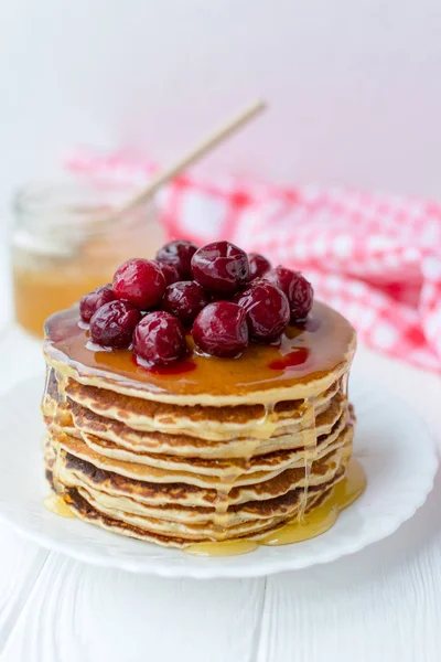 Petit déjeuner sain. Empilement de délicieuses crêpes maison au miel et cerise sur plaque blanche — Photo