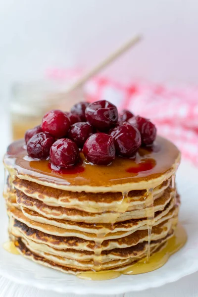 Pequeno-almoço saudável. Pilha de deliciosas panquecas caseiras com mel e cereja no prato branco — Fotografia de Stock