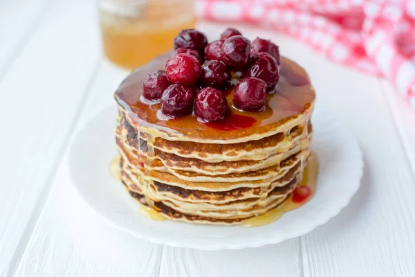 Desayuno saludable. Pila de deliciosos panqueques caseros con miel y cereza en plato blanco — Foto de Stock