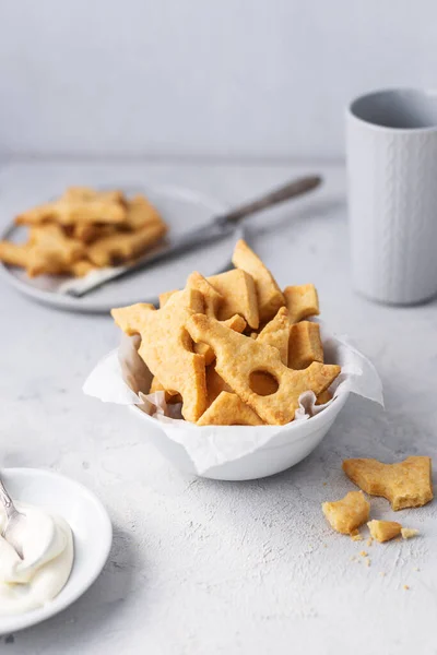 Cheese crackers, salty snack concept. Cookies, piece of cheese on a gray background