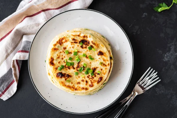 Siyah arka planda Çin usulü leziz soğanlı krep. Bir yığın kızarmış yeşil soğanlı krep. Siyah fotoğraf