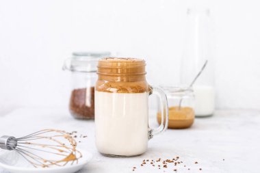 Beyaz arka planda bardakta son moda dalgona kahvesi. Kore kahveli ve köpüklü kahve içiyor. Yeni popüler yiyecek ve içecek trendi. Seçici odak