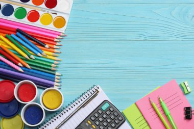 school and office supplies. school background. colored pencils, pen, pains, paper for  school and student education on blue wooden background. top view clipart