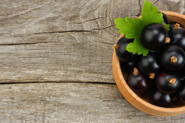ahşap kase eski ahşap zemin üzerine yeşil yaprak Siyah frenk üzümü