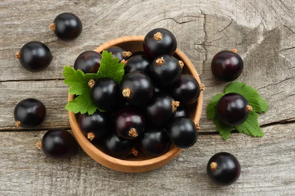 ahşap kase eski ahşap zemin üzerine yeşil yaprak Siyah frenk üzümü