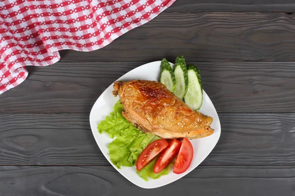 Grilled chicken fillet with tomato on plate on wooden table