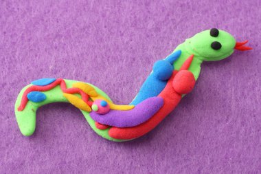 Pembe arka planda plastik yılan. Kil modelleme. Yılanın içinde.