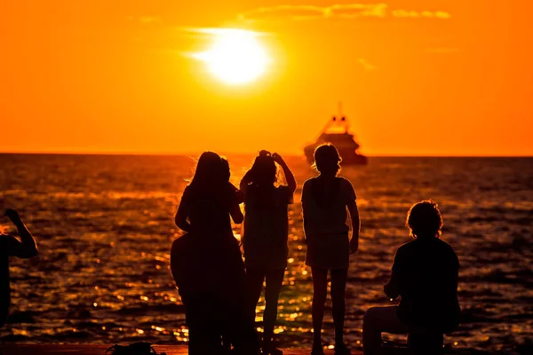 Deniz ve yat ufukta altın gün batımında insan siluetleri