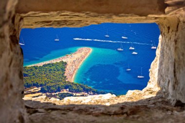Zlatni rat beach aerial view through stone window clipart