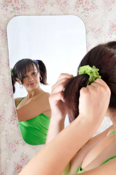 Pretty girl with pony-tails looks at the mirror