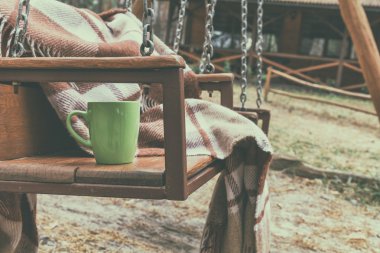 Yün battaniye ve kupa ile ahşap salıncak